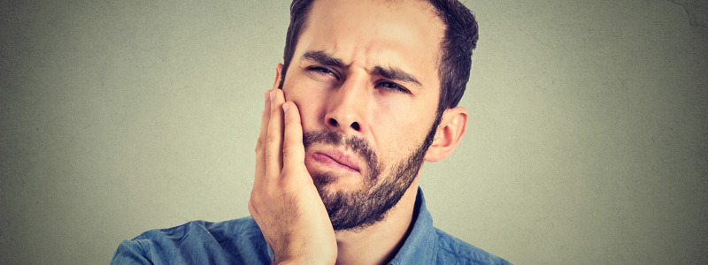 a man with toothache is holding his cheek