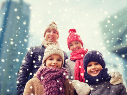 family photo with mom, dad, son, and daughter standing outwside in the snow and winter gear