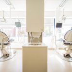 Two dental chairs separated by a large cabinet with a sink in a dental office that has the latest dental technology