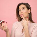 woman holding cupcake licking her finger